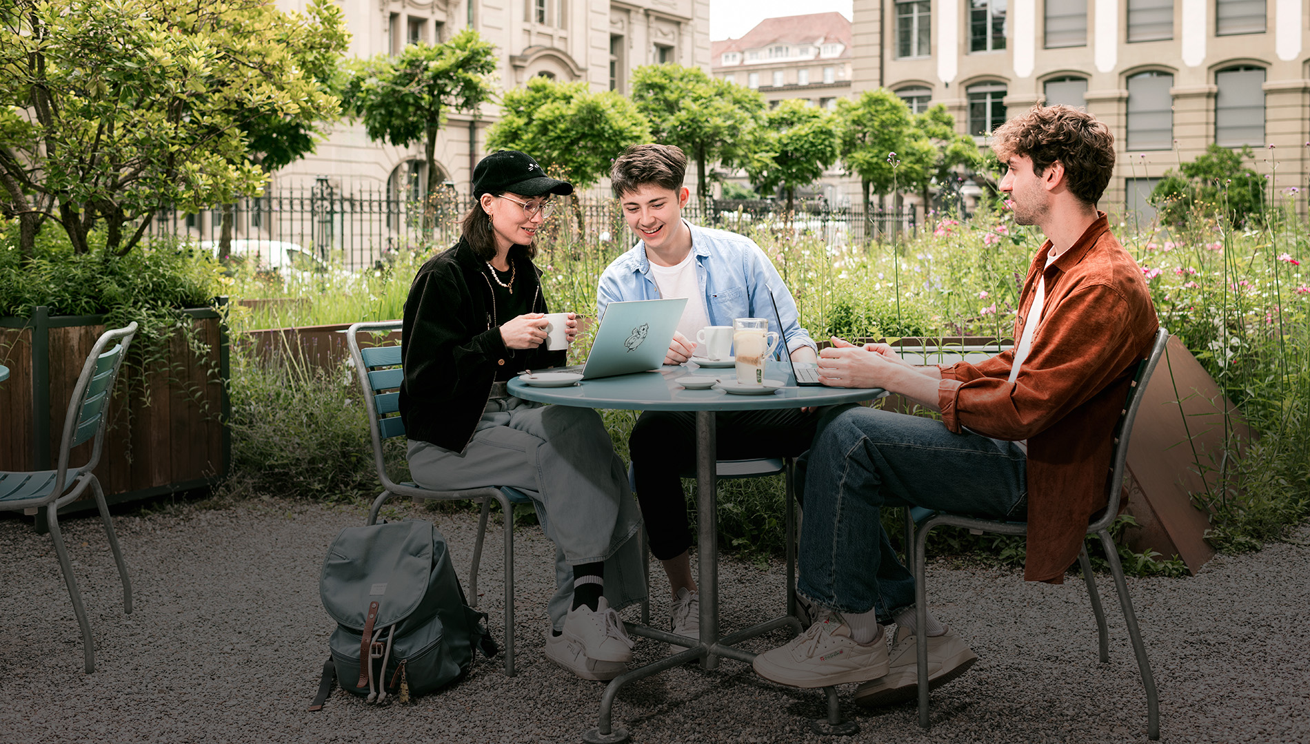 Des étudiants sont assis à une table, boivent du café et discutent.