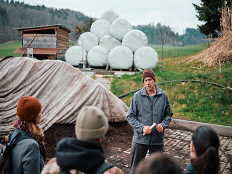 Landwirt und Delegation vor Biogasanlage